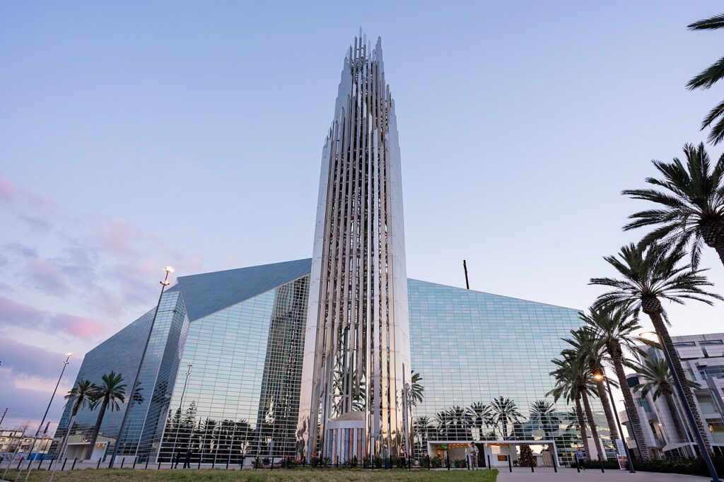 Exterior shot of Crystal Cathedral, a large glass building with a spire.