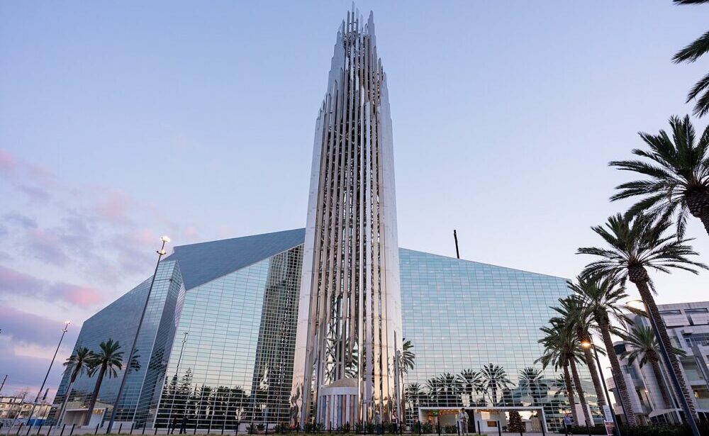 Exterior shot of Crystal Cathedral, a large glass building with a spire.